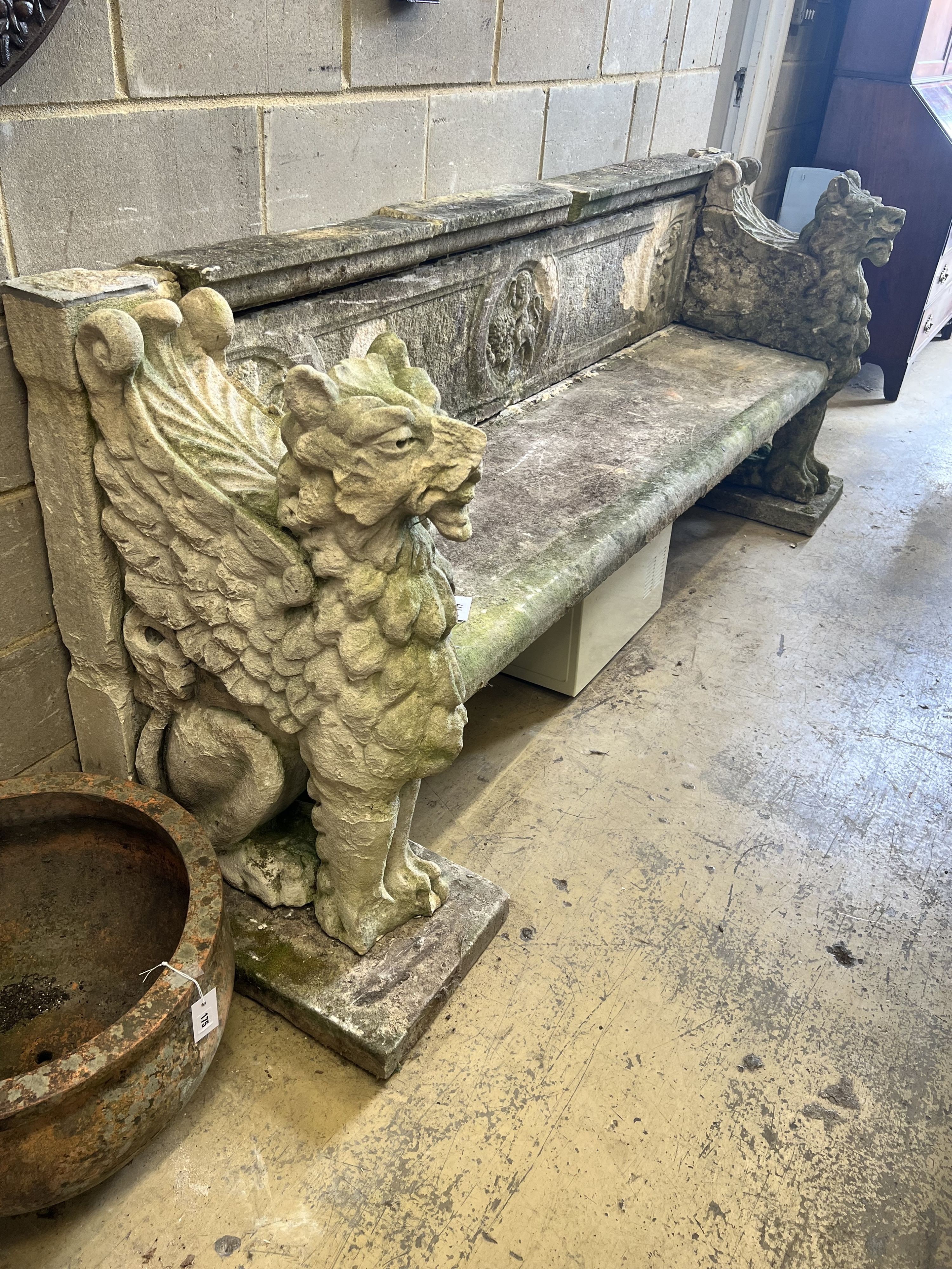 A monumental reconstituted stone winged lion or griffin garden bench, width 250cm depth 66cm height 96cm, in need of restoration